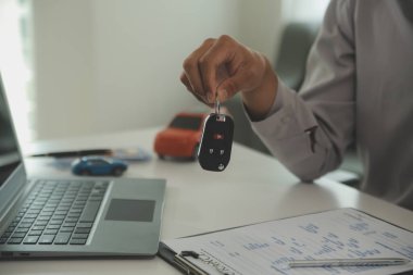 Genç bir adam araba satıcısından bir anahtar alır. Atölye, kredi kartı, sigorta, satış, araba satın alma ve finans konseptinde bir arabanın kirası veya satışı için anlaşma yaptıktan sonra.