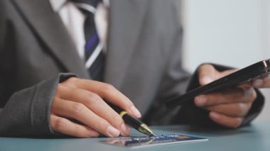 Elinde akıllı bir telefonla kalem ve yazı tutan bir işadamı.