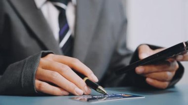 Kredi kartı tutan bir iş adamı ve ödeme için akıllı telefon kullanıyor.