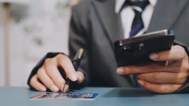 Masada kredi kartı ve akıllı telefon tutan bir adam var.