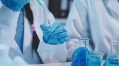 Yakın plan. Elinde mavi bir sıvıyla bir bilim adamının eline. Bilim ve eğitim kavramı. Araştırma konsepti