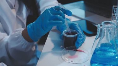 Laboratuvar çalışanı mavi sıvıyla test yapıyor.