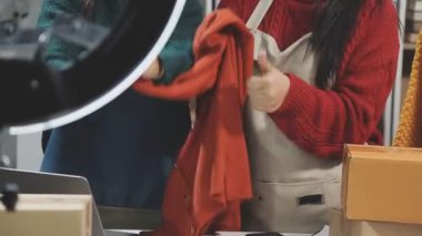 Kırmızı elbiseli ve şapkalı genç bir kadın elinde küçük bir poşet kahve tutuyor.