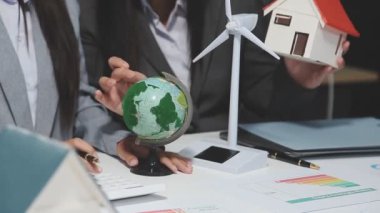 Ofisinde yeşil enerji modeli olan dijital tablet kullanan genç iş kadını.