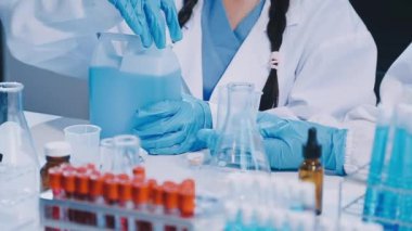 Koruyucu eldivenli ve gözlüklü kadın doktor laboratuarda deney tüpüyle çalışıyor..