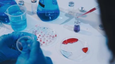 Mavi takım elbiseli bilim adamı ve eldivenler laboratuarda çalışıyor..