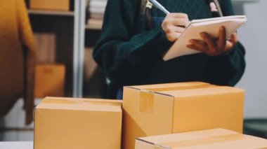 Üniformalı bir kadın evde paket kutularıyla, teslimat servisiyle uğraşıyor.