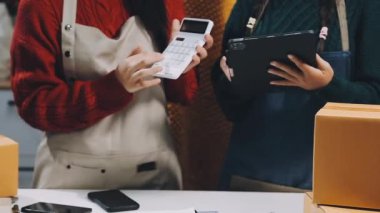 Dükkanda cep telefonu kullanan ve internetten kredi kartı ödeyen bir kadın.