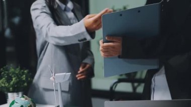 İş kadını dizüstü bilgisayarını tutuyor ve iş yerinde iş arkadaşıyla konuşuyor.
