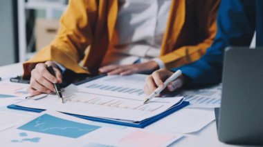 İş adamları masadaki mali verileri tartışıyor ve analiz ediyorlar.