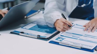 Yakın plan. Masada bir panoyla çalışan doktorların elleri.