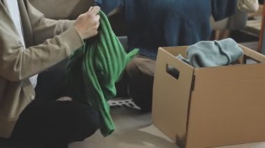 Kutu için kıyafet paketleyen bir adam.