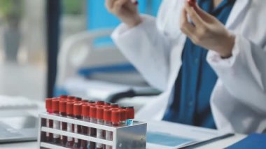 Laboratuvar önlüklü doktor elinde kan örneği tutuyor.