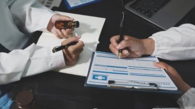 Elinde dosya ve reçeteyle hastanede ilaç yazan doktor.