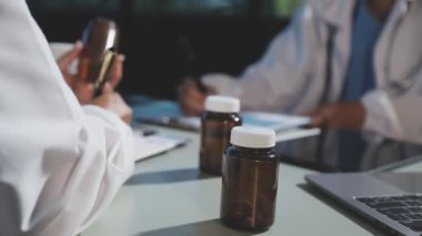 Elinde tablet ve arka planda bir şişe hapla bir doktorun fotoğrafını çek..