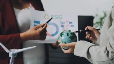 Ofis masasının yanında elinde kağıt ve küre tutan genç adam.