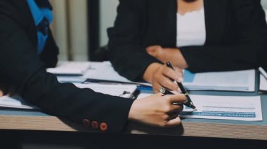 Takım elbiseli genç bir iş kadını ofiste bir not defteri ve kalem tutuyor.