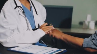 Tıp ceketli doktor klinikte bir hastayla konuşuyor.