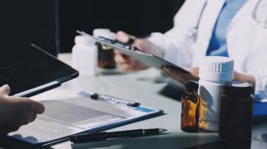 Doktor elinde ilaç şişesiyle bir tablet tutuyor.