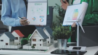 Emlakçı ev modelini tutuyor ve bir modelle emlak planını tartışıyor..