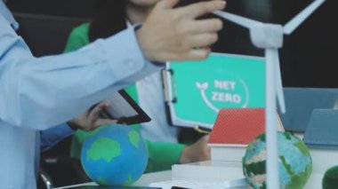 Genç Asyalı kadın küreyi tutuyor ve ofiste yeşil enerji gösteriyor..
