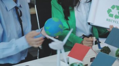 Takım elbiseli genç bir kadın elinde bir kese kağıdıyla geri dönüşüm sembolü tutuyor.