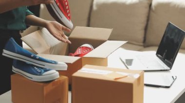Elinde karton kutu tutan mavi gömlekli bir adam çevrimiçi alışveriş ve müşteri hizmetlerine ürün hazırlamak için evden çalışıyor.
