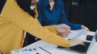 İş ekibi toplantıda dizüstü bilgisayardan mali raporu tartışıyor