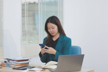 Modern ofiste cep telefonu kullanan genç bir iş kadını.