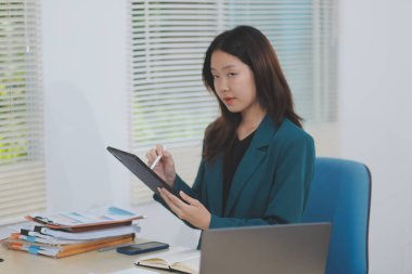 Şirket ofisinde tablet bilgisayarda çalışan Asyalı profesyonel iş kadını.