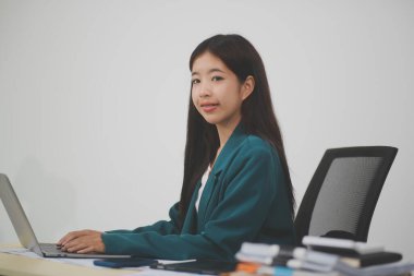 Güzel Asyalı iş kadını, ofise yerleştirilmiş evraklarla birlikte tablet ve dizüstü bilgisayar kullanıyor..