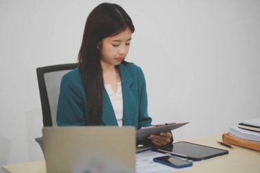 Asyalı iş kadını dizüstü bilgisayarla çalışıyor, pazarlama raporu ve hesap makinesi dokümanı masanın üzerinde, finansal raporları analiz etmek için online iş planına, e-ticarete yatırım yapıyor..