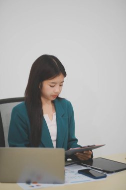 Asyalı iş kadını dizüstü bilgisayarla çalışıyor, pazarlama raporu ve hesap makinesi dokümanı masanın üzerinde, finansal raporları analiz etmek için online iş planına, e-ticarete yatırım yapıyor..