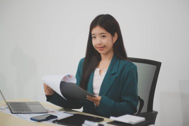 Asyalı iş kadını dizüstü bilgisayarla çalışıyor, pazarlama raporu ve hesap makinesi dokümanı masanın üzerinde, finansal raporları analiz etmek için online iş planına, e-ticarete yatırım yapıyor..