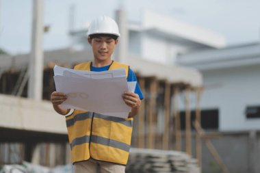 İnşaat alanındaki Mühendislik Danışmanlığı elinde planları tutuyor. İnşaat müfettişi. Yeni binanın inşaat sahası çizimi ve iş akışı