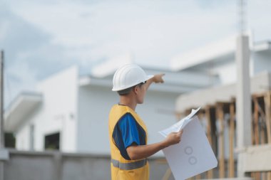 İnşaat alanındaki Mühendislik Danışmanlığı elinde planları tutuyor. İnşaat müfettişi. Yeni binanın inşaat sahası çizimi ve iş akışı