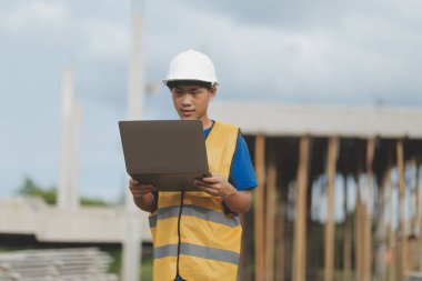 Dizüstü bilgisayarı tutan işçi ya da mühendis ve deponun içindeki konteynırları kontrol ediyor