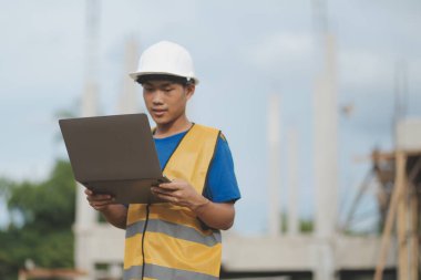 Dizüstü bilgisayarı tutan işçi ya da mühendis ve deponun içindeki konteynırları kontrol ediyor