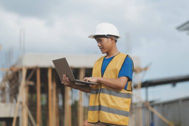 Dizüstü bilgisayarı tutan işçi ya da mühendis ve deponun içindeki konteynırları kontrol ediyor