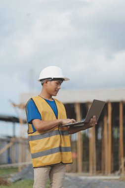 Dizüstü bilgisayarı tutan işçi ya da mühendis ve deponun içindeki konteynırları kontrol ediyor