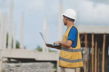 Dizüstü bilgisayarı tutan işçi ya da mühendis ve deponun içindeki konteynırları kontrol ediyor