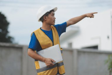 Dizüstü bilgisayarı tutan işçi ya da mühendis ve deponun içindeki konteynırları kontrol ediyor