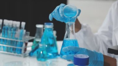 Kimya laboratuvarında mavi bir sıvıyla çalışan bilim adamı..