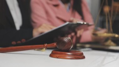 Avukat, yargıç tokmak ve avukat ofiste hukuk üzerinde çalışıyorlar. Avukatın elinde tokmak, hukuk ve adalet kavramı var..