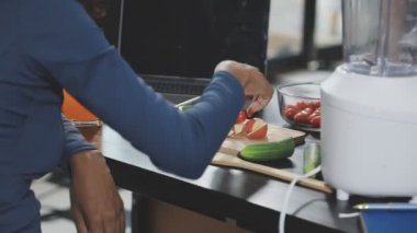 Genç bir kadın mutfakta smoothie hazırlıyor.