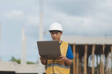 Dizüstü bilgisayarı tutan işçi ya da mühendis ve deponun içindeki konteynırları kontrol ediyor