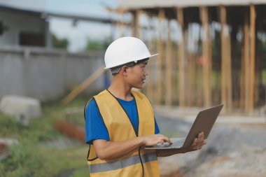 Dizüstü bilgisayarı tutan işçi ya da mühendis ve deponun içindeki konteynırları kontrol ediyor
