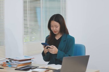 Modern ofiste cep telefonu kullanan genç bir iş kadını.