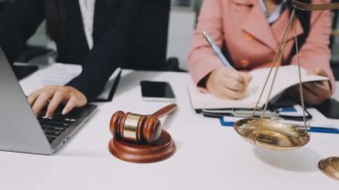Avukat, mahkeme salonundaki müvekkillere dizüstü bilgisayar ve belge ile çalışıyor.