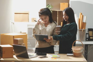 Başlangıçta küçük işletme KOBİ 'si, akıllı telefon veya tablet kullanan girişimci Afrikalı kadın paket ürün kutusu hazırlamak için çevrimiçi alışveriş siparişini alır ve kontrol eder.